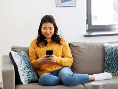 Woman sitting on couch holding cellphone